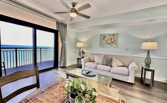 Oceanfront balcony with two black chairs overlooking beach, ocean, and cloudy sky